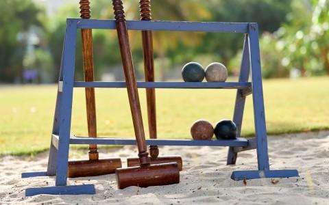Wooden croquet set with mallets and balls on sandy ground, ideal for leisure play.