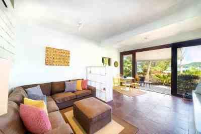 Modern living room with L-shaped sofa and terrace view, leading to garden and mountains