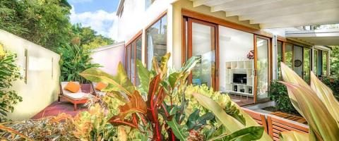 Modern home patio with orange lounge chair and lush tropical foliage visible.