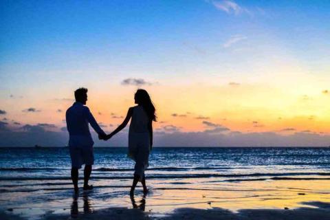 Romantic couple holding hands on a serene beach at sunset