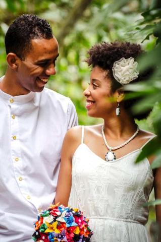 Joyful couple in semi-formal attire with origami bouquet celebrating event outdoors