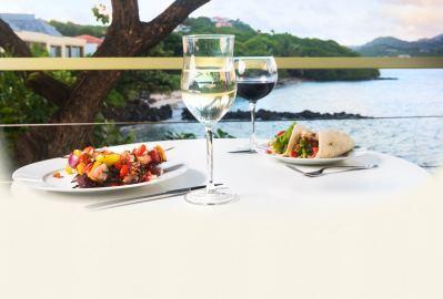 Dining table with food and wine overlooking serene waterfront