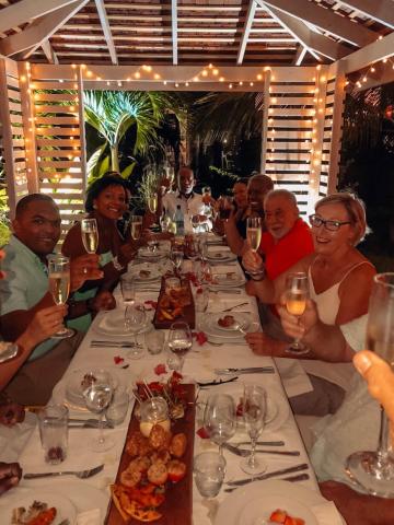 Group toast at outdoor dinner under pergola with string lights, festive ambiance