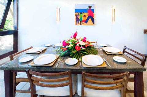 Modern dining room table set for six with colorful centerpiece and art.