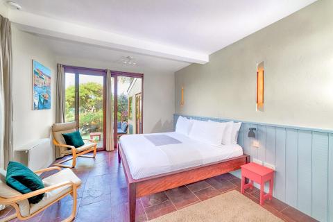 Cozy well-lit bedroom with white bedding, wooden furniture, and balcony view.