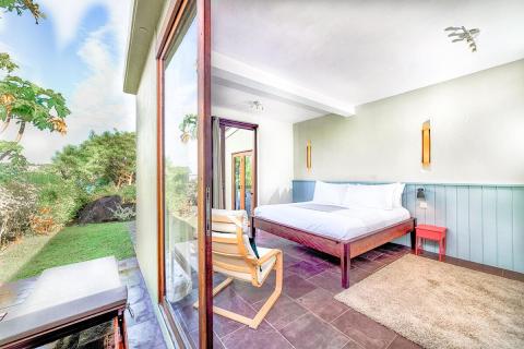 Serene bedroom with open door to garden, plush carpet, and modern decor.