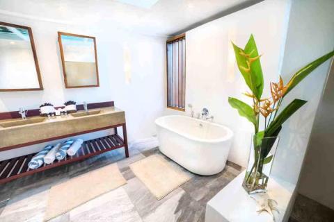 Modern bathroom with freestanding tub, dual sinks, and floral decor.