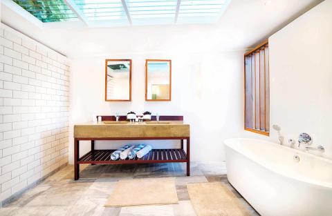 Modern bathroom with freestanding tub, wood-framed mirror, and skylights.