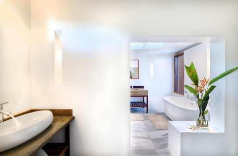 Modern bathroom with oval sink, wooden marble counter, and freestanding bathtub.