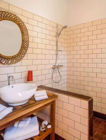 Modern minimalistic bathroom with white tiles, wooden vanity, and round mirror.