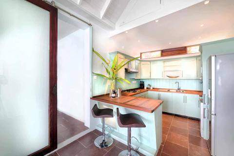 Modern kitchen with teal cabinets, wooden counters, and high stools at island.