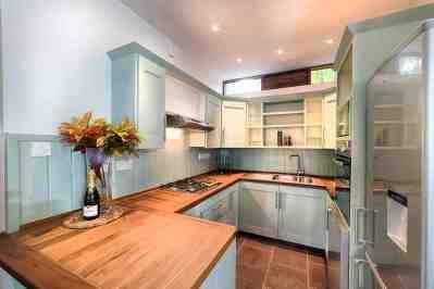 Modern U-shaped kitchen with white cabinets, dark countertops, and wooden breakfast bar.