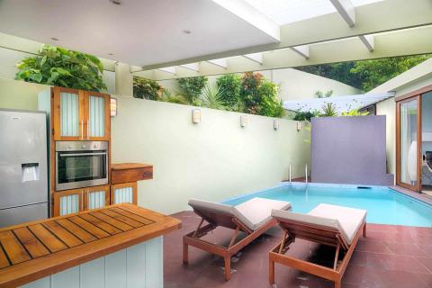 Modern indoor-outdoor living space with kitchen and relaxation area by pool