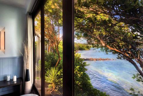 Stylish room interior and vibrant tropical beach view through window