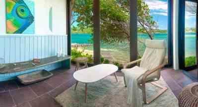 Indoor-outdoor space with modern furniture overlooking a tranquil beach