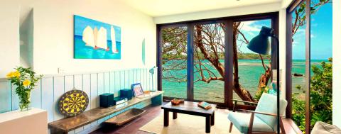 Cozy seaside home interior with bench, dart board, and ocean view through glass doors