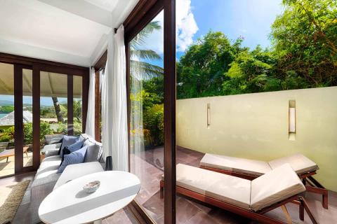 Luxurious indoor lounge and private outdoor space with ocean view and lush greenery.