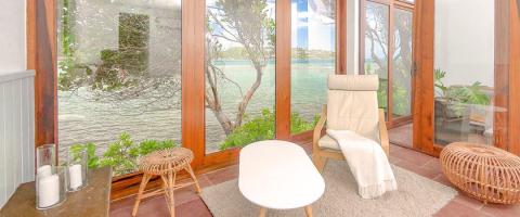 Serene indoor lounge with lake view, comfy chair, and glass windows.