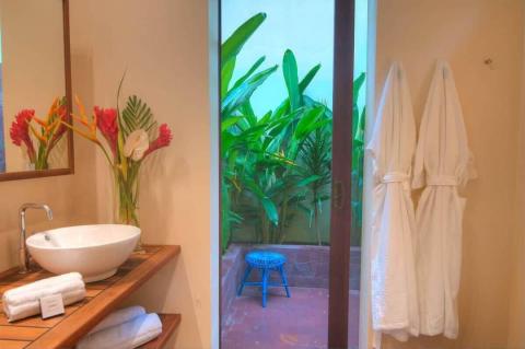Stylish bathroom with wooden vanity, tropical flowers, and lush outdoor view.