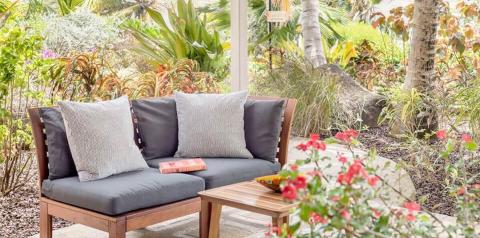 Cozy garden loveseat with cushions, surrounded by lush tropical plants and flowers.