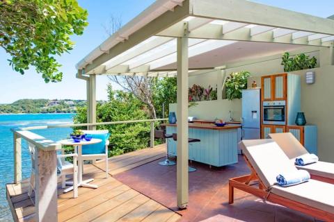 Ocean view outdoor living area with wooden deck, pergola, and kitchen
