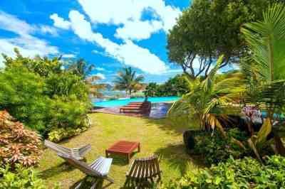 Luxurious tropical resort with pool, palm trees, and lounge chairs under sunny sky