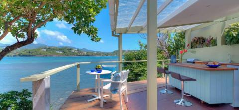 Scenic outdoor deck with dining area, sea view, and bar, ideal for relaxation.