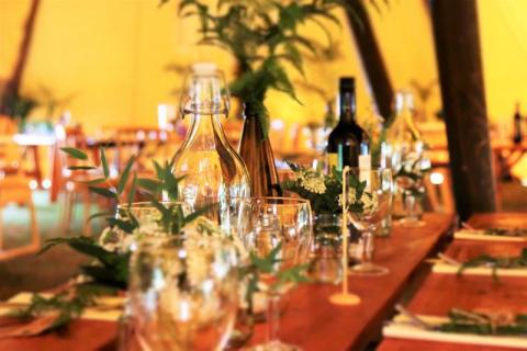 Elegant table setting for a wedding with floral decor and wine under cozy lighting.