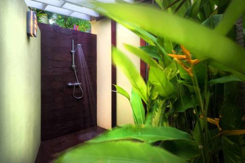 Secluded outdoor shower with tropical plants and ambient lighting