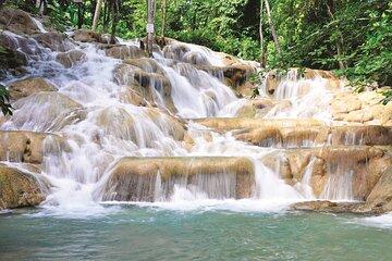 Stunning terraced waterfall with clear green pool, surrounded by lush, vibrant foliage.