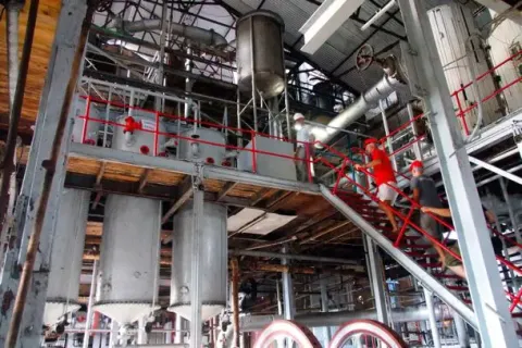 Visitors Touring an Industrial Facility with Complex Machinery and Operations Industrial facility with complex machinery, large tanks, and visitors wearing safety gear.