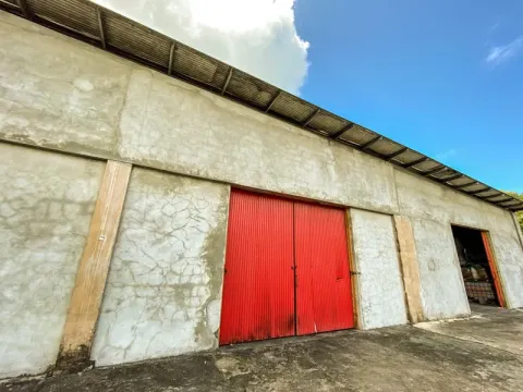 Weathered Industrial Warehouse with Striking Red Doors Exterior of an aged concrete industrial building with red corrugated metal doors