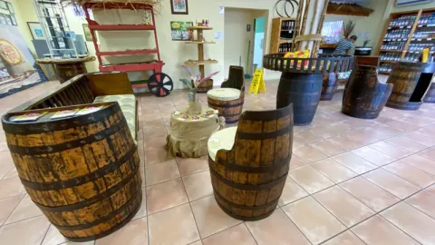 Rustic Distillery Tasting Room with Repurposed Barrel Furniture Cozy rustic tasting room with repurposed barrel furniture, tiled floor, and a decorative setup.