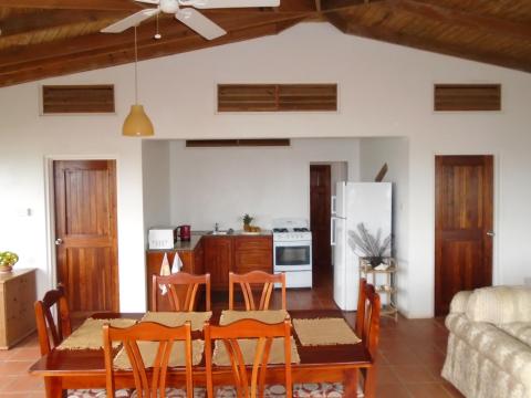 Rustic home interior with wooden furniture, open kitchen, and vaulted ceiling.