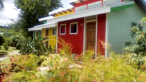 Colorful tropical building with yellow, red, green walls and lush greenery on sunny day.