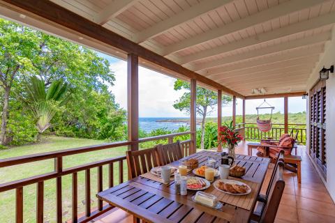 Scenic porch breakfast setup with sea view, hammock, and vibrant flowers