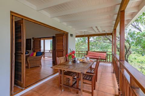 Charming outdoor terrace with wooden dining set and lush greenery.