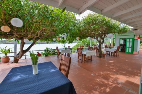 Terrace dining area with white lanterns overlooking water.