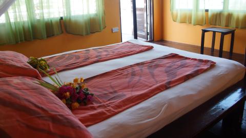Cozy bedroom with large bed, orange walls, and natural light.