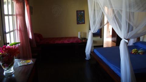 Rustic bedroom with two beds, wooden floors, and floral decorations for a serene ambiance.