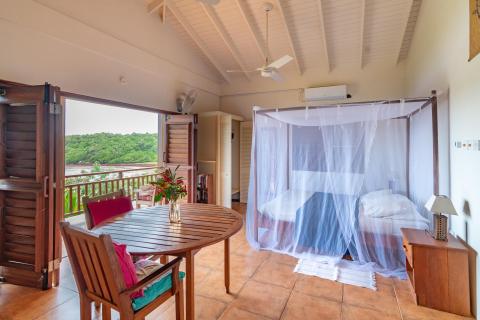 Luxurious open-plan bedroom with mosquito net, lush views, and balcony for a serene ambiance.
