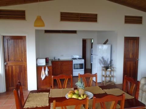 Rustic kitchen-dining area with wooden table, chairs, and high ceilings