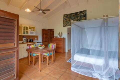 Cozy tropical vacation rental interior with bed, kitchenette, and dining area.