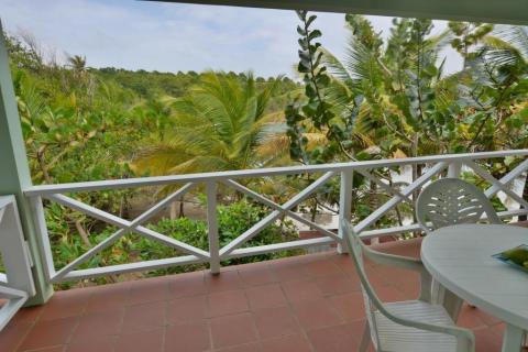 Scenic tropical balcony view with lush greenery and white furniture for relaxation.