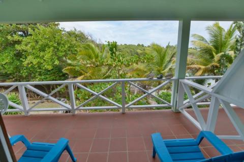 View from balcony with blue chairs overlooking lush tropical garden, ideal for relaxation.