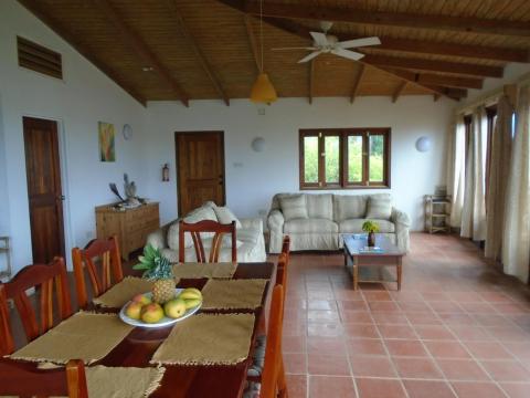 Spacious living room with terracotta floors, wooden beams, and rustic decor