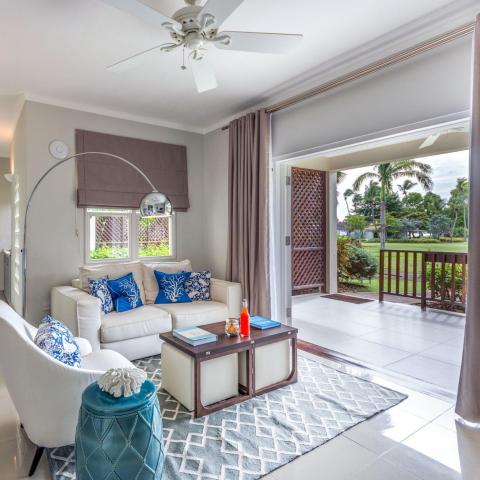 Stylish living room with white sofa, armchair, and garden view through sliding doors.