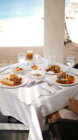 Beachfront breakfast with ocean view, eggs on toast, fruits, and coffee