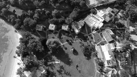 Aerial B&W photo of coastal area with buildings, palm trees, and beach