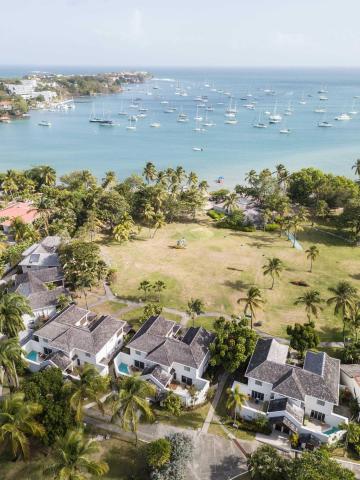 Coastal luxury homes with pools near beach and sailboats from above